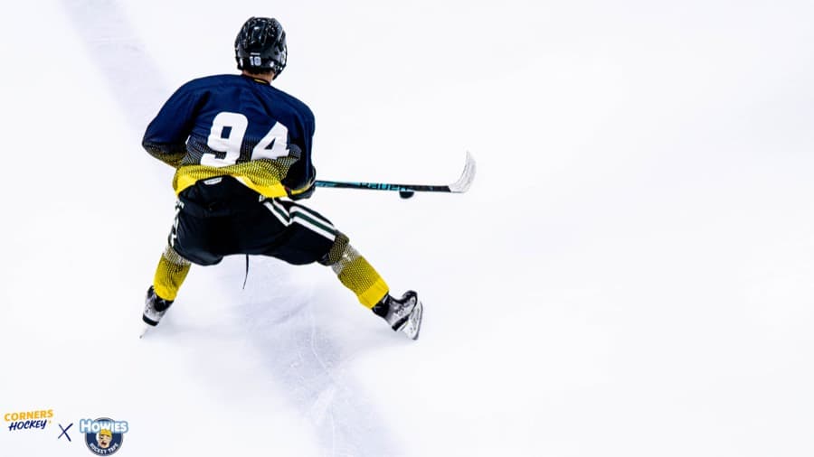 A Corners Hockey player in navy and gold driving up open ice